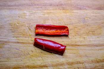 Rote Chilischote längs halbiert und entkernt auf einem Holzbrett