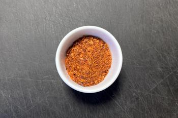 Rote Chiliflocken in einer weißen Schale auf dunkler Arbeitsfläche