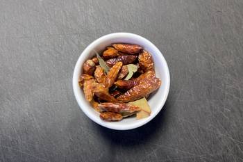 Getrocknete rote Chilischoten in einer weißen Schale auf dunkler Arbeitsfläche