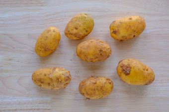Rohe, ungeschälte Kartoffeln auf einem dunklen Brett
