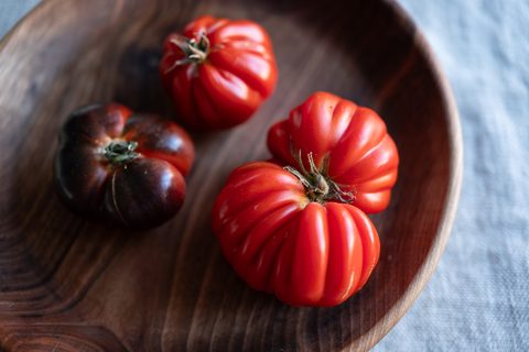Rote und dunkle Ochsenherz-Tomaten in einer Holzschale