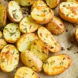 Halbierte Ofenkartoffeln mit knusprig gebräunter Schnittfläche und Rosmarin auf Backpapier