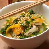 Pho Ga Reisnudelsuppe mit Hähnchen, Karottenstreifen und Sesam in weißer Schale