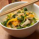 Vietnamesische Pho Ga Reisnudelsuppe mit Huhn, Karotten, Thai-Basilikum, Koriander, Sojasprossen und Sesam, serviert in einer weißen Schale mit Essstäbchen