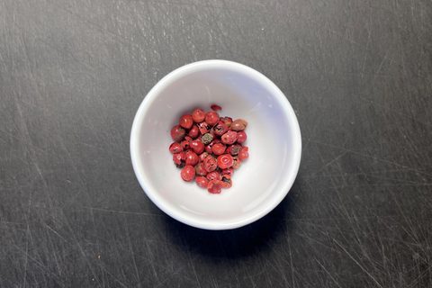 Rosa Pfefferbeeren in einer weißen Schale auf dunkler Arbeitsfläche