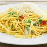 Knoblauchspaghetti mit geriebenem Parmesan, Chili und Petersilie auf weißem Teller